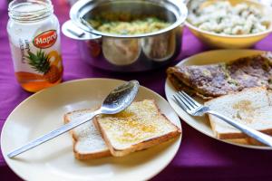 a table with two plates of toast with spoons and forks at SaffronStays Villa 270, Dapoli in Dapoli