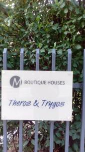 a sign in front of a bush at Theros & Trygos Boutique Houses - ATH Airport in Artemida