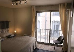 1 dormitorio con cama, ventana y silla en Résidence RIVES DE LOIRE, en Blois