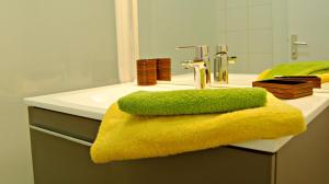 a bathroom with a yellow towel on a sink at Little Suite - Théo in Lille