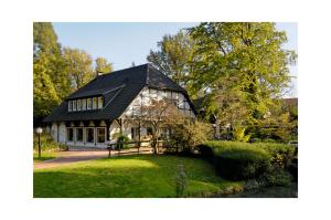 a house with a black roof on a green yard at Ferienwohnung Brunnenhaus in Bad Sassendorf