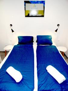 2 letti in una camera con piumone blu di Trenta Apartman Bükfürdő a Bük