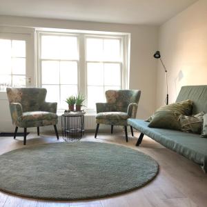 uma sala de estar com um sofá, 2 cadeiras e um tapete em No6a Luxe design appartement in historisch hart Dordrecht ALLES dichtbij! em Dordrecht