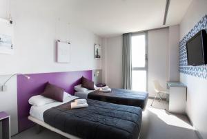 バルセロナにあるTwentytu Hostel Barcelonaのベッド2台とテレビが備わるホテルルームです。