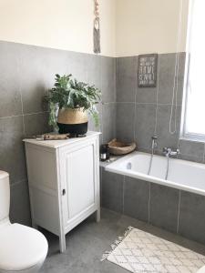 a bathroom with a tub and a toilet and a plant on a cabinet at Villa Rowan in Ostend
