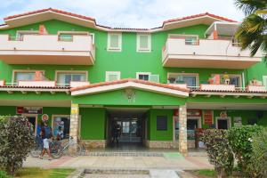 a green building with people standing outside of it at Djasal Moradias in Santa Maria