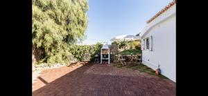 a brick patio with a white house and a tree at Casa Cora Con Jacuzzi in Breña Baja
