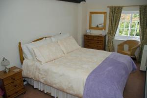 a bedroom with a bed and a dresser and a window at 2 Hope Cottage in Spilsby