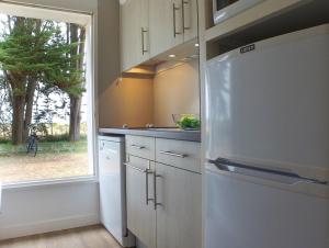 a kitchen with a white refrigerator and a window at VVF Résidence Île de Ré Ars-en-Ré in Ars-en-Ré