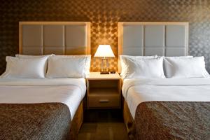 St. Paul卡塔尔塔圣保罗酒店的一间带两张床和一张带灯的桌子的酒店房间