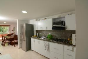La cuisine est équipée de placards blancs et d'un réfrigérateur en acier inoxydable. dans l'établissement Acogedor Apartamento 2 Habitaciones S31, à Envigado
