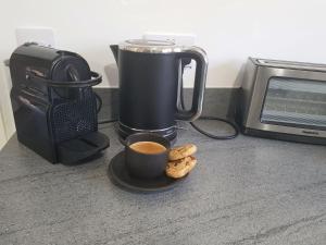 eine Tasse Kaffee und Kekse auf einem Teller neben einem Toaster in der Unterkunft North Colchester Homestay in Colchester
