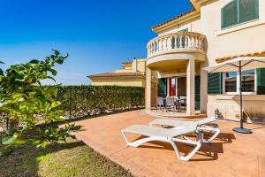 un patio con una silla blanca y una sombrilla en Residence Club El Paraiso, en Sa Ràpita