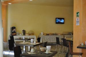 a dining room with tables and chairs and a tv on the wall at Guerrini Hotel in Castiglioncello