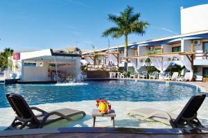 a swimming pool with two chairs and a hotel at Sueds Plaza in Porto Seguro