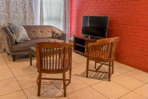 salon z kanapą, 2 krzesłami i telewizorem w obiekcie Cape Pine Guest House w mieście Kuilsrivier