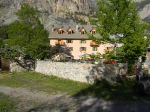 a large house in front of a stone wall at Auberge La Cleida in Névache
