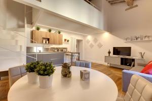 a living room with a white table and a kitchen at Mamo Florence - Mattonaia Apartment in Florence