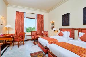 Habitación de hotel con 2 camas y escritorio en The Ummed Jodhpur Palace Resort & Spa, en Jodhpur