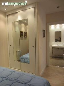 1 dormitorio con espejo, lavabo y cama en apartamento el mirador en Ezcaray