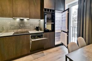 a kitchen with dark wood cabinets and a table at City Center Loft in Kaunas