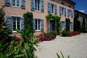 un bâtiment avec des fleurs et des plantes devant lui dans l'établissement La Maison d'Anais, à Vic-en-Bigorre