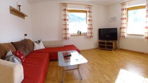 sala de estar con sofá rojo y TV en Ferienhaus Manuela, en Neustift im Stubaital