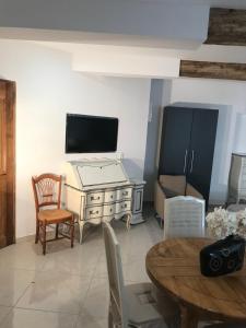 uma sala de estar com uma televisão e uma mesa e cadeiras em Chambre Familiale du Couvent em Narbonne