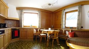 cocina con mesa y sillas y 2 ventanas en Ferienhaus Manuela, en Neustift im Stubaital