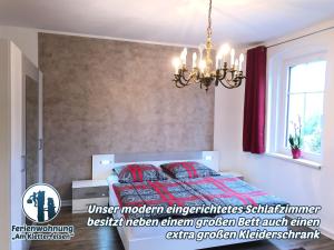 Schlafzimmer mit einem Bett mit roten Kissen und einem Kronleuchter in der Unterkunft Ferienwohnung "Am Kletterfelsen" in Krauschwitz
