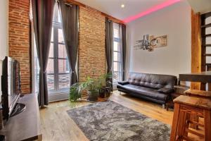 a living room with a leather couch and a brick wall at TOULOUSE DUPLEX PLACE DU CAPITOLE in Toulouse +2 photos