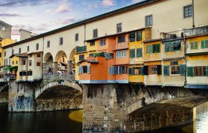 a bridge over a river with a group of buildings at Florence Prestige Apartments ZANOBI 55 in Florence