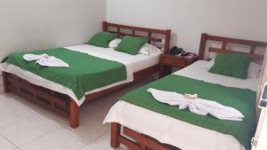 two beds with green and white sheets and towels on them at Hotel Orquídea Neiva in Neiva
