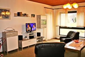 a living room with a flat screen tv and two chairs at Ferienwohnung Schaefer in Michelstadt