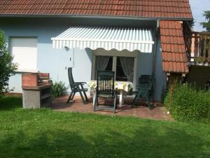 a patio with two chairs and an awning on a house at Les gîtes du lindenberg in Dambach
