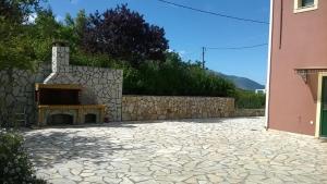 a stone patio with a fireplace next to a wall at Villa Eleftheria in Karavomylos