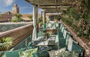 un restaurante con sillas verdes y mesas en la azotea en La Sultana Marrakech, en Marrakech