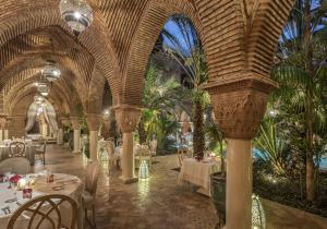 a restaurant with tables and chairs in a room with palm trees at La Sultana Marrakech in Marrakesh