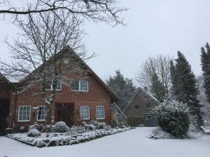 une maison en briques rouges avec de la neige au sol dans l'établissement Ferienwohnung Sandhoege, à Börger