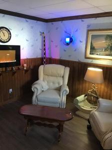 a living room with a chair and a table and a clock at Auberge La Cote d'Or in Petite-Rivière-Saint-François