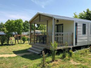 uma pequena casa com um alpendre e um deque em Camping Au Pré de l'Étang em Sainte-Foy