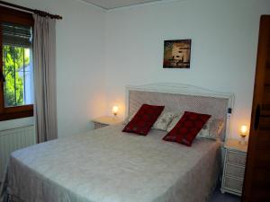 ein Schlafzimmer mit einem Bett mit zwei roten Kissen darauf in der Unterkunft Las Bellotas in Moraira