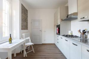a kitchen with white cabinets and a white table at Tata's Home in Cernobbio