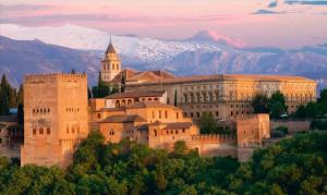 a large building on a hill with mountains in the background at Gran Via Balconies in Granada