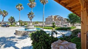 a fountain in a park with palm trees and a building at OASİS AT AYFİLON in Rizokarpaso