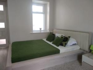 1 dormitorio con 1 cama grande con almohadas verdes en City Center Apartment en Tiflis
