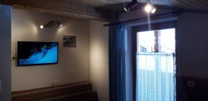 a living room with a tv on the wall next to a window at Haus Fichtenblick in Auffach