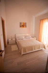 a white bedroom with a bed and a window at Apartments Svjetlana in Trogir