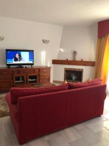 a living room with a red couch and a flat screen tv at La Siesta de Mijas Golf 174 in Fuengirola