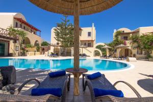 a pool with two chairs and a table with an umbrella at Smaragdi in Perivolos